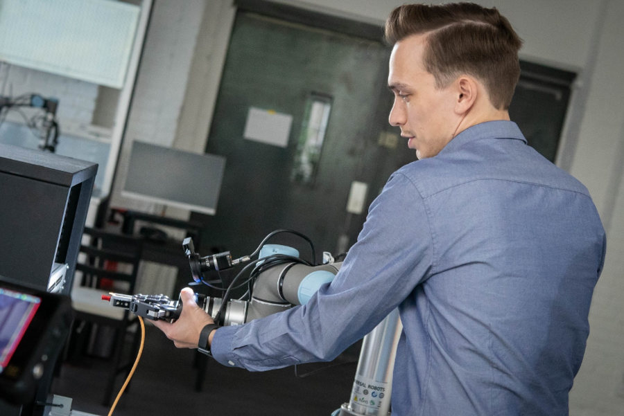 Employee trains MIRAI-controlled robot. A MIRAI-controlled robot can be trained by human hands via demonstration; neural networks then process the data obtained. Courtesy Micropsi Industries