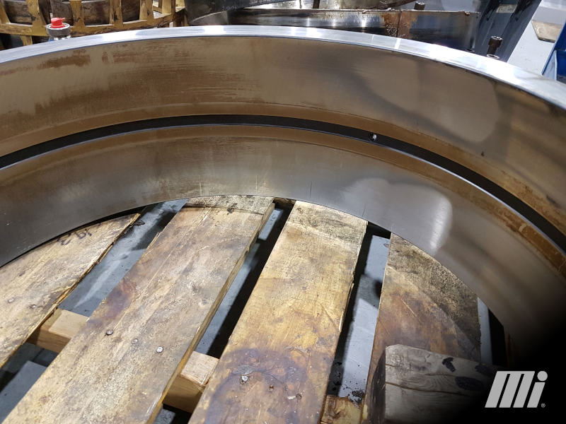 This outer ring raceway shows roller skidding when entering and leaving the load zone. This is suspected to be caused by prolonged periods of reduced loading in conjunction with overlubrication. Instances of reduced loading of a cylindrical bearing application combined with excessive grease will increase the likelihood of skidding.