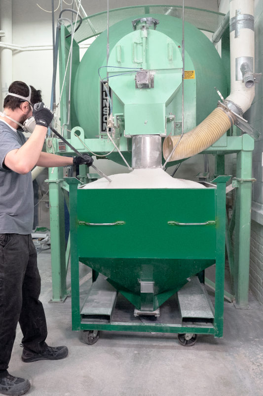The mixer discharges uniformly blended product into a mobile bin, which is wheeled to low-pressure extruders and the hot-melt casting process. Dust is collected during discharge.