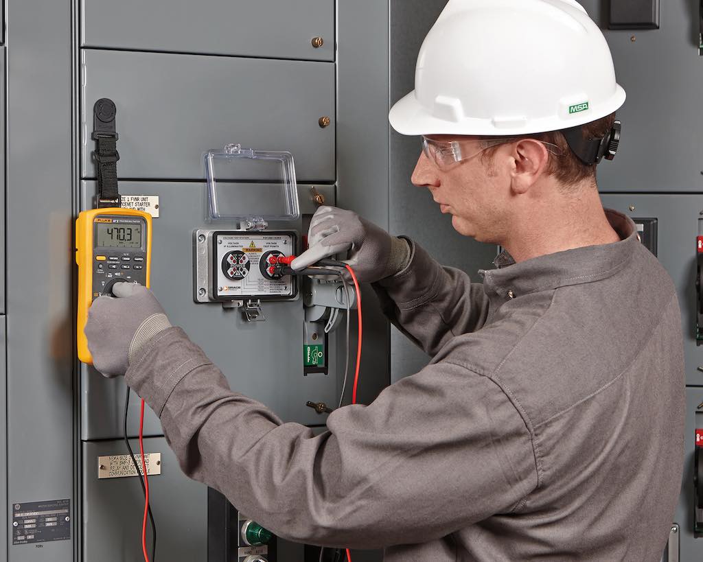 Figure 1: A qualified electrician taking a voltage reading using a voltage test station permanent electrical safety device and his portable test instrument. Courtesy: Grace Technologies