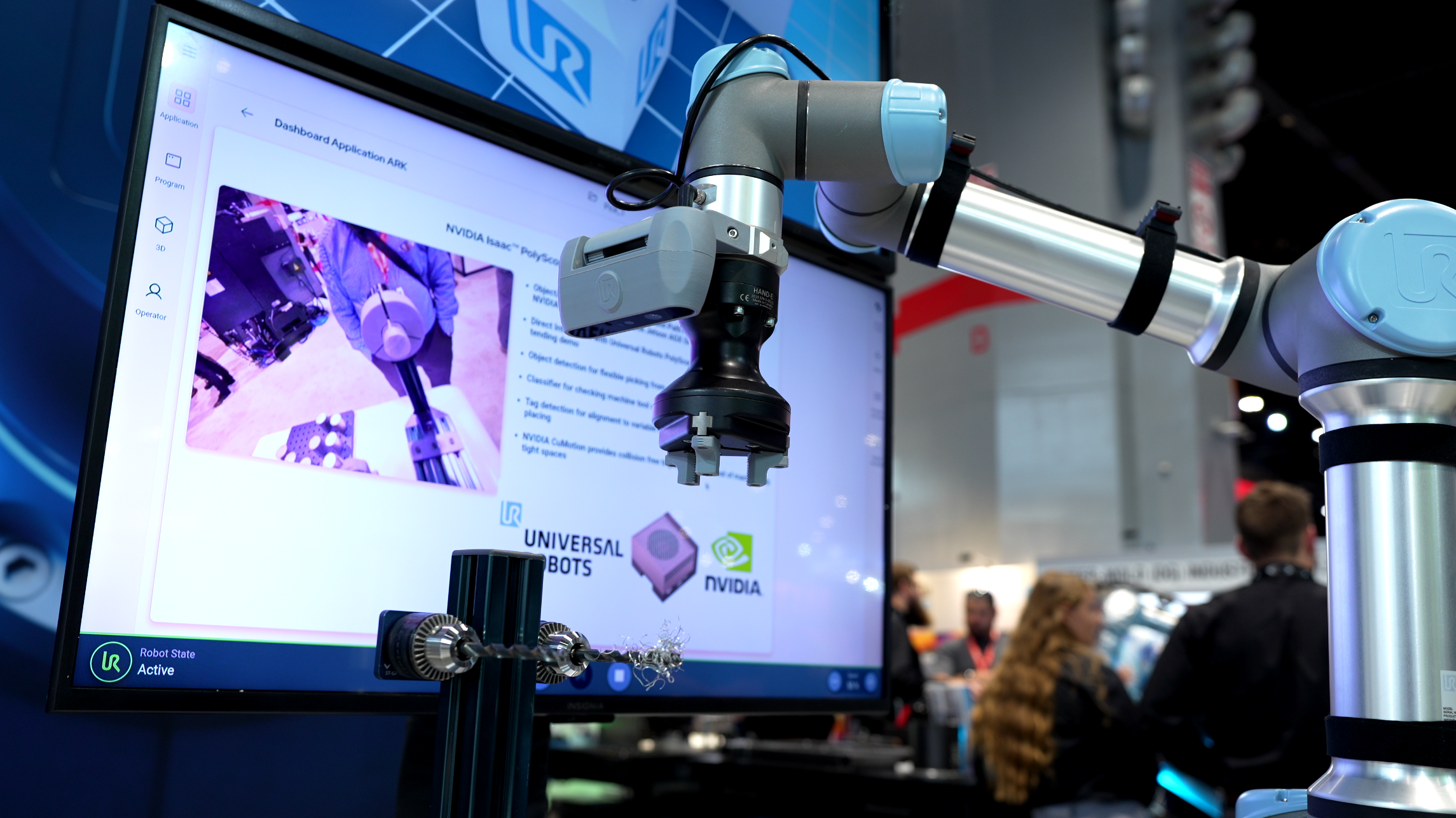 Figure 1: Universal Robots launched the AI Accelerator. The toolkit is enabled by UR's next-generation software platform PolyScope X and is powered by NVIDIA Isaac accelerated libraries and AI models, running on the NVIDIA Jetson AGX Orin system-on-module. The toolkit also includes the Orbbec Gemini 335Lg 3D camera. Depicted here from the ROSCon exhibition 2024 is a demo of the AI Accelerator with a computer numerical control machine tending application using a UR5e. Courtesy: Universal Robots
