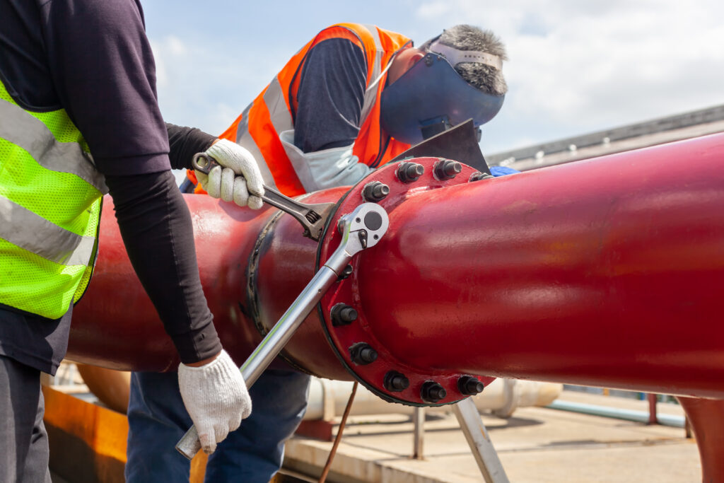 A worker installing and tightening bolts and nuts of a flange system. Courtesy: Teadit