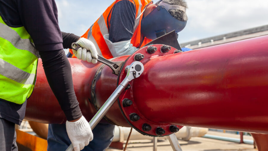 A worker installing and tightening bolts and nuts of a flange system. Courtesy: Teadit