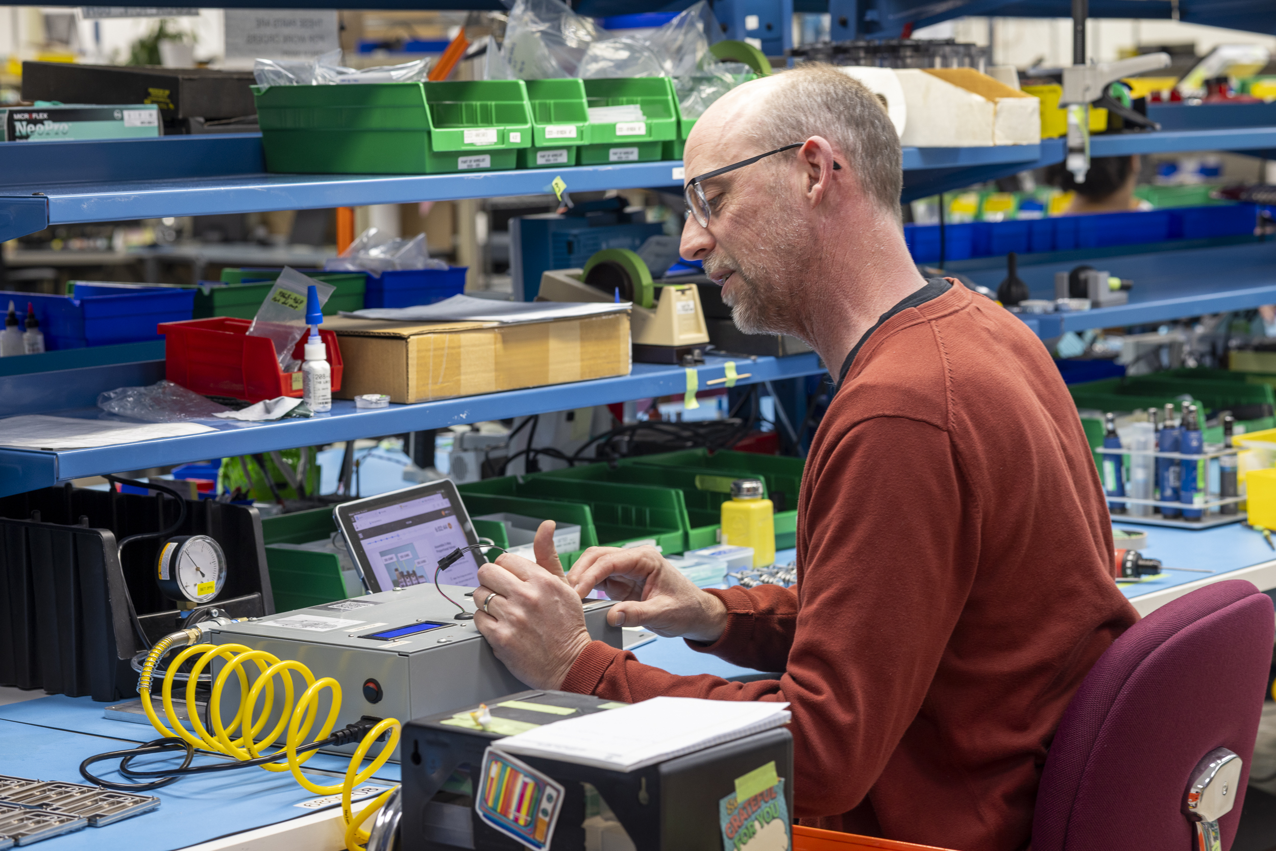 Figure 3: Operator calibrates a machine with work instructions displayed on a tablet in the background. Courtesy: Pico MES