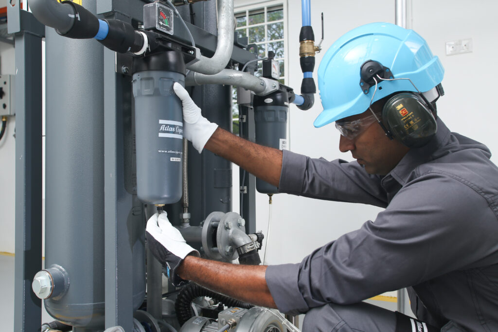 Figure 2: Installing filter drains, as this service technician does, is a part of air compressor maintenance. Courtesy: Atlas Copco Compressors