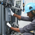 Figure 2: Installing filter drains, as this service technician does, is a part of air compressor maintenance. Courtesy: Atlas Copco Compressors